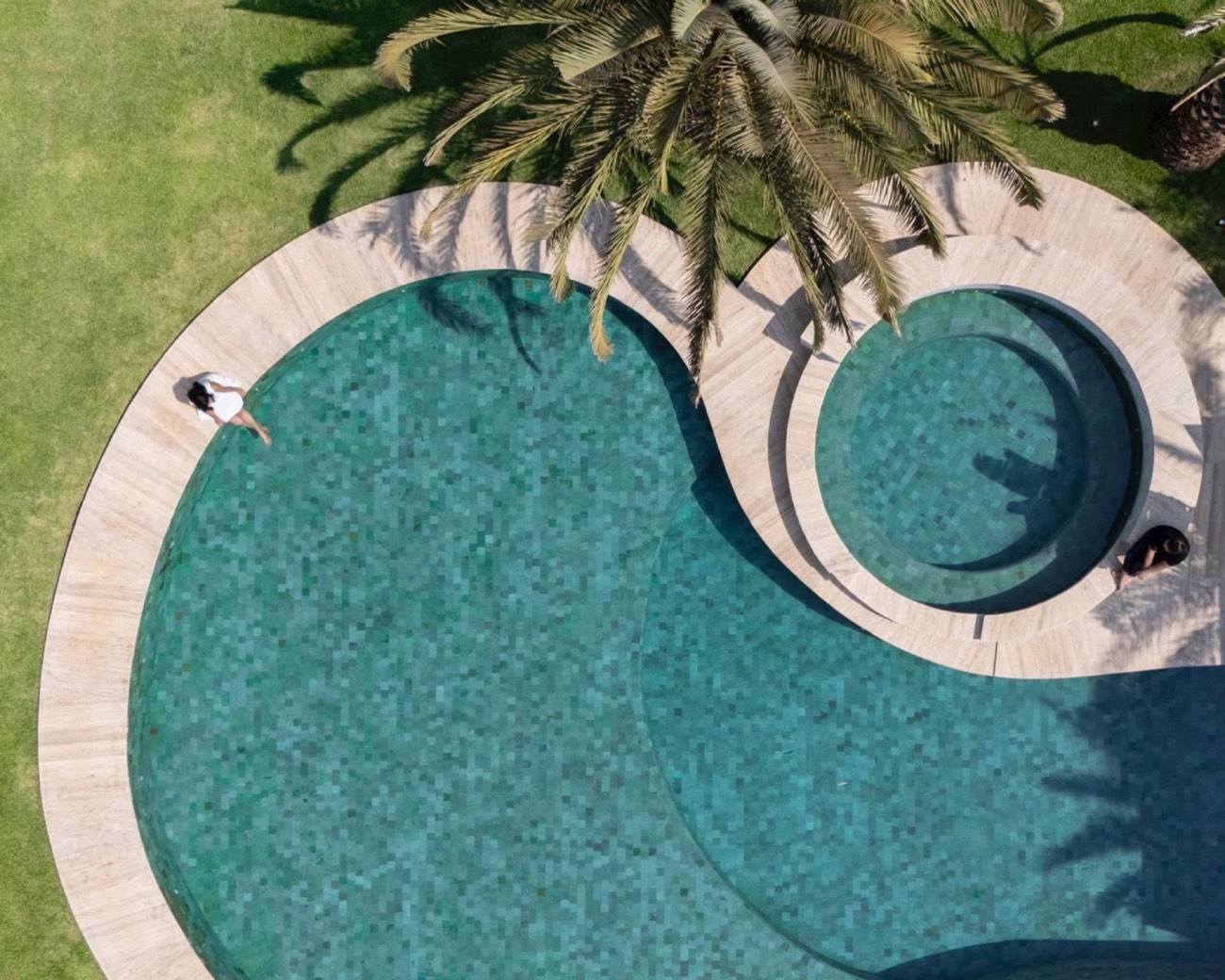 Piscina orgânica vista de cima com borda e deck em travertino